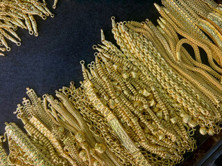 An extensive array of intricate gold chain is meticulously arranged on a dark surface, showcasing...