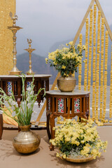 Elegant wedding decor featuring floral arrangements, brass vases, and traditional Indian elements,...