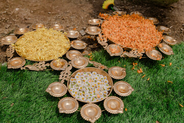 Floral displays in gold bowls sit on lush green grass. The yellow, orange, and white flowers create...