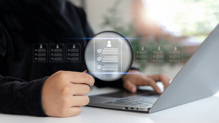 Business HR using a laptop to analyze digital resumes with a magnifying glass icon, concept of online recruitment, candidate screening, and hiring process.