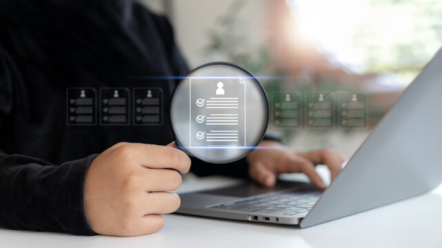 Business HR using a laptop to analyze digital resumes with a magnifying glass icon, concept of online recruitment, candidate screening, and hiring process.
