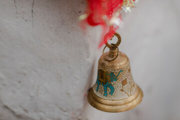 Ornate brass bell with an elephant design hangs against a textured wall, showcasing detailed...