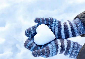 Hands in knitted mittens with heart shaped snow. Winters Day. Valentine's Day