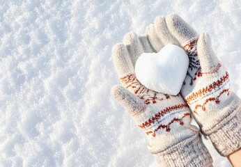Hands in knitted mittens with heart shaped snow. Winters Day. Valentine's Day