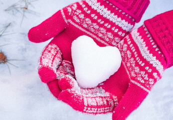 Hands in knitted mittens with heart shaped snow. Winters Day. Valentine's Day