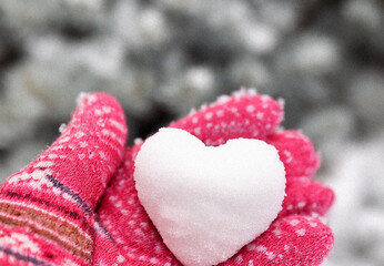 Hands in knitted mittens with heart shaped snow. Winters Day. Valentine's Day