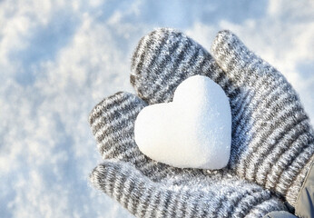 Hands in knitted mittens with heart shaped snow. Winters Day. Valentine's Day