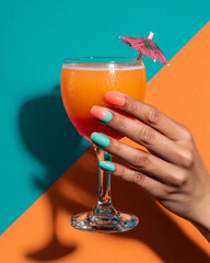 Summer nails in ombre coral and teal polish holding tropical cocktail with paper umbrella