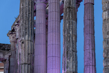Roman temple illuminated with purple light at dusk