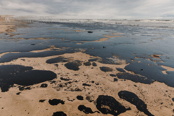 Oil spill contaminates beach shoreline, showing the environmental damage and urgency of marine pollution cleanup.