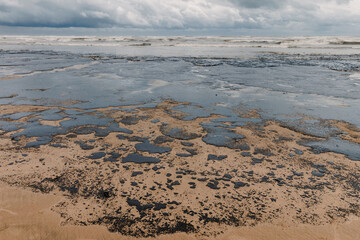 Oil spill contaminates beach, showing the environmental damage and urgency of marine pollution cleanup.