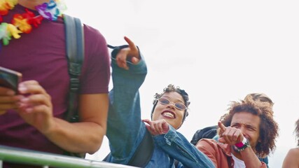 Camera tracks along group of young friends waiting behind barriers at entrance to music festival site - shot in slow motion