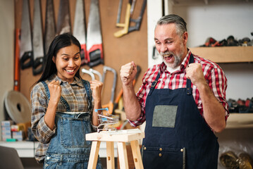 Senior Carpenter and Asian Woman Using Laptop to Sell Handmade Woodwork Products on E-commerce...