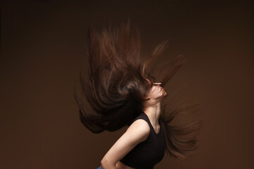 Teenage girl with healthy long hair on brown background