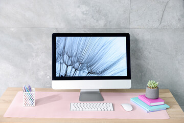 Stylish workplace with computer and pink mousepad on wooden table indoors