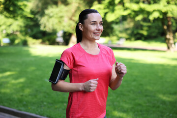 Sporty woman with armband running in park