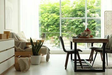 Wooden table, chairs, sofa and decor in dining room. Interior design