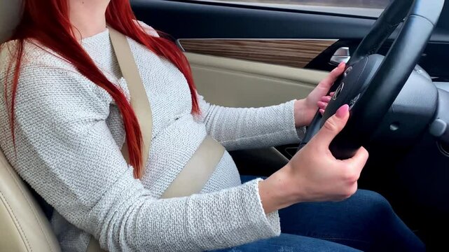 Pregnant woman driving car on road,buckling up seat belt.daily life during pregnancy.modern motherhood,responsible travel,mobility,independence