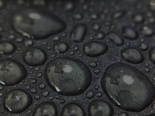 Macro Shot of Water Droplets on Textured Dark Surface with Reflections.
