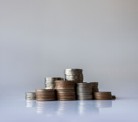Stacks of mixed coins on white reflective surface with copy space representing savings, investment,...