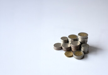 Stacks of mixed coins on white reflective surface with copy space representing savings, investment, and financial growth