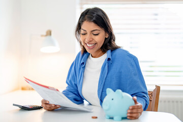 Woman engages in budgeting and financial planning at home with a piggy bank and paperwork in a...