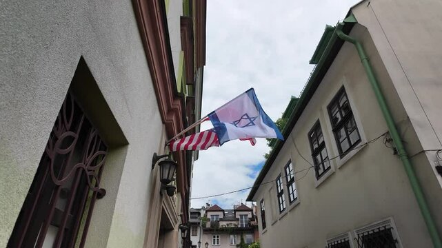Flags of Israel and the USA waving in a narrow European street. High quality 4k footage