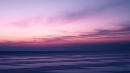 Obraz premium A serene scene of a pink and purple sunset over the ocean with soft clouds and calm water surface