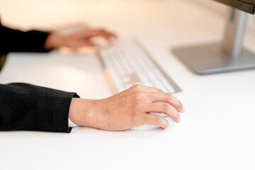 Employee working on a computer with a mouse in a modern office setting during the day