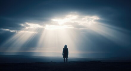 Solitary figure under dramatic sky with sun rays breaking through clouds