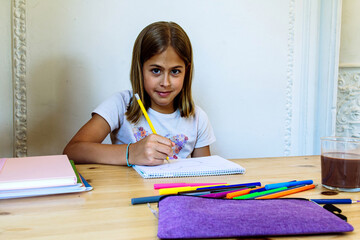 Young girl drawing with colored pencils on notebook at home
