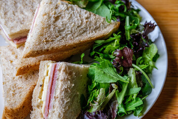 Homemade Ham and Cheese Sandwich In Sliced Brown Bread With Green Salad Leaves