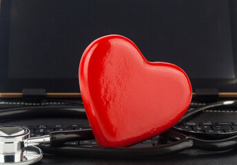 Stethoscope and red heart computer, tablet as background.