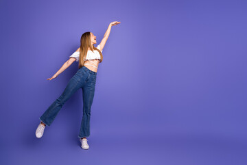 Lovely cheerful woman posing in trendy clothing with playful gestures on vibrant purple background