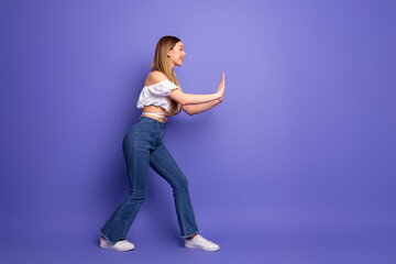 Young woman posing in stylish casual outfit with hand gesture against a vibrant violet background