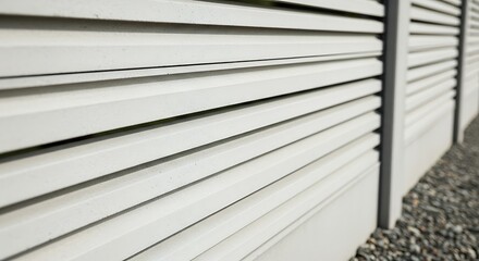 Obraz premium Close-up of a modern white fence with horizontal slats, casting shadows in bright sunlight.