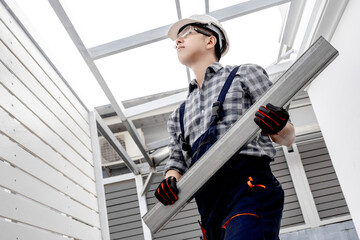 Asian man construction worker in protective workwear installing steel beam at building site. Male...