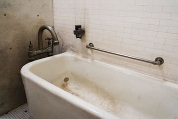 A vintage bathtub in a white tile room.