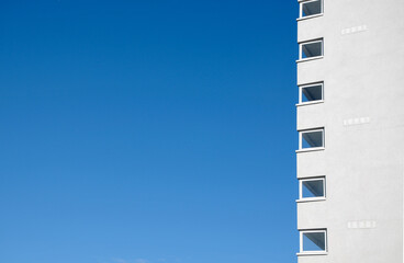Abstract view of a high rise residential apartment block against a clear blue sky.