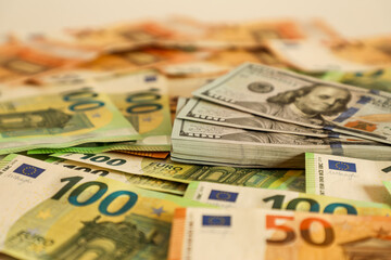 Close-up of scattered 100 and 50 denomination US dollar and euro banknotes, forming a vibrant background that symbolizes wealth, global finance, international trade, and economic power.