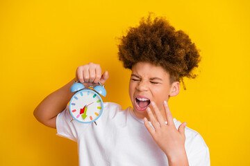 Cheerful boy holding a colorful alarm clock showing a playful morning gesture, set against a...