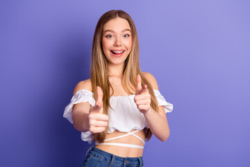 Happy young woman smiling and gesturing enthusiastically while pointing fingers forward with...