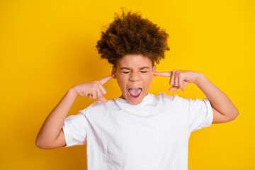 Excited boy in white t-shirt gesturing and shouting against vibrant yellow background demonstrating...