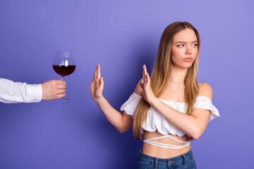 Young woman declines a glass of wine on a vibrant purple background representing a lifestyle concept