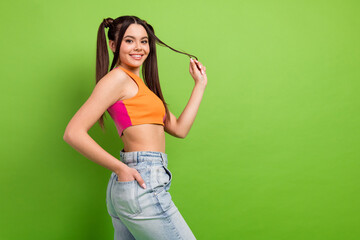 Portrait of a young woman with playful hairstyle and bright clothing against green background...