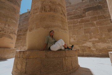 Tourist resting at the base of an ancient egyptian column