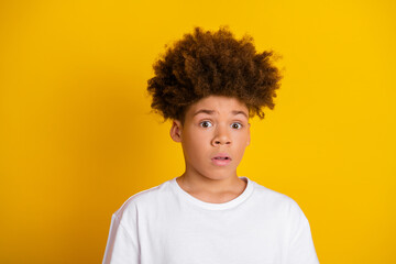 Surprised young boy against yellow background wearing a white shirt with curious expression, ideal...