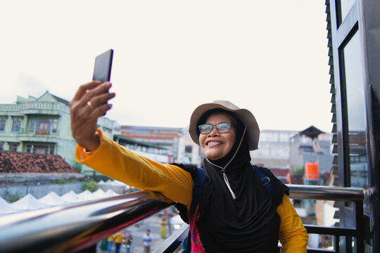 Smiling Woman Taking a Selfie Outdoors at Teras Malioboro in Sunny Day