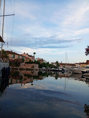 Charming Mediterranean port at sunset, bathed in golden light. Pastel houses line a calm canal with...