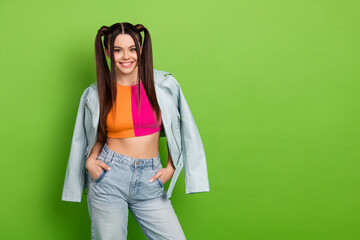 Cheerful young woman with trendy hairstyle in vibrant outfit posing confidently against a vivid...